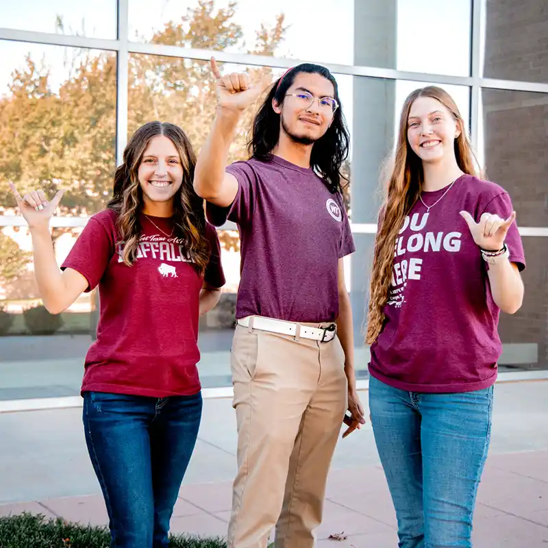 Three WT students showing the buffalo hand sign