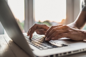 man using and typing on laptop