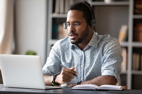 man wearing headphones studying with laptop
