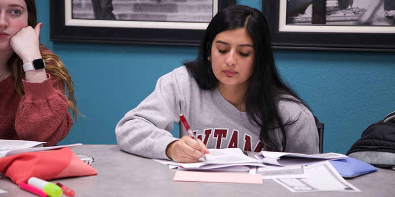 Female in a WTAMU sweatshirt writing